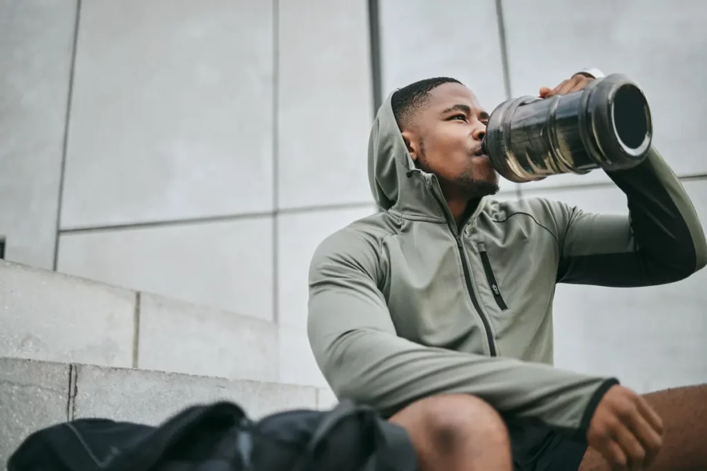 A guy sitting down post workout drinking a recovery drink