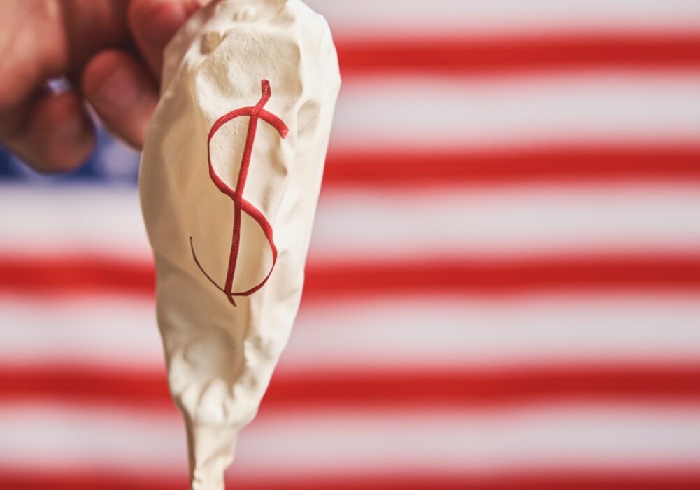 Deflated balloon with a dollar sign in front of an American flag